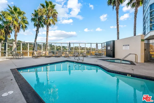 a view of a swimming pool with a patio and palm trees