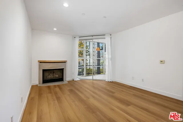a view of empty room with wooden floor and fireplace