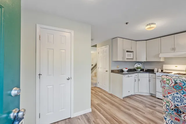 a kitchen with stainless steel appliances granite countertop a stove top oven a sink dishwasher and a refrigerator with wooden floor