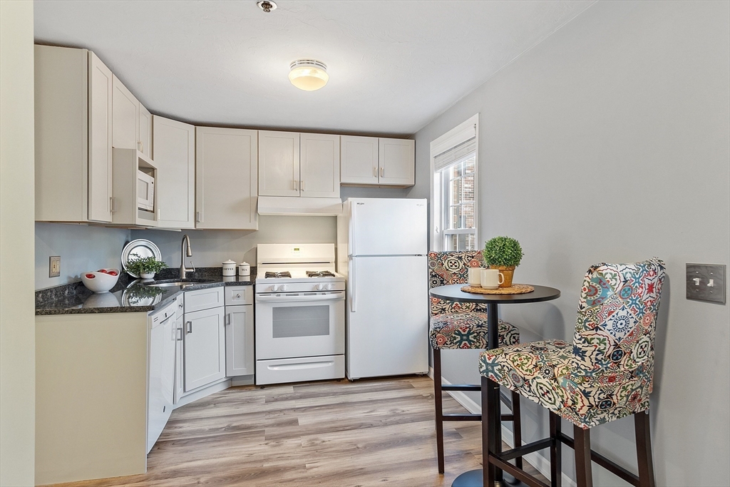 278 Manning Street, Unit 603 Hudson, MA 01749 - Photo 5 of 34 a kitchen with stainless steel appliances granite countertop a refrigerator a stove a sink dishwasher and white cabinets with wooden floor