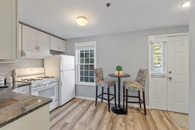 a kitchen with stainless steel appliances granite countertop a stove top oven a sink dishwasher and a dining table with wooden floor