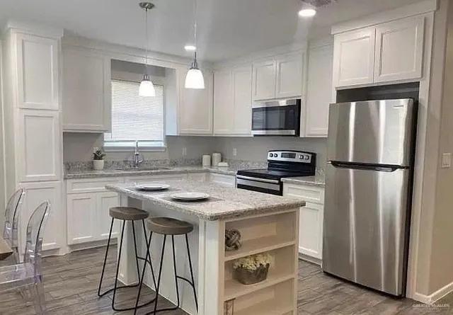 a kitchen with stainless steel appliances granite countertop a refrigerator a stove a sink and a microwave