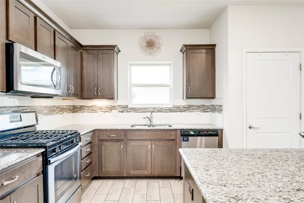 a kitchen with granite countertop a stove top oven and cabinets