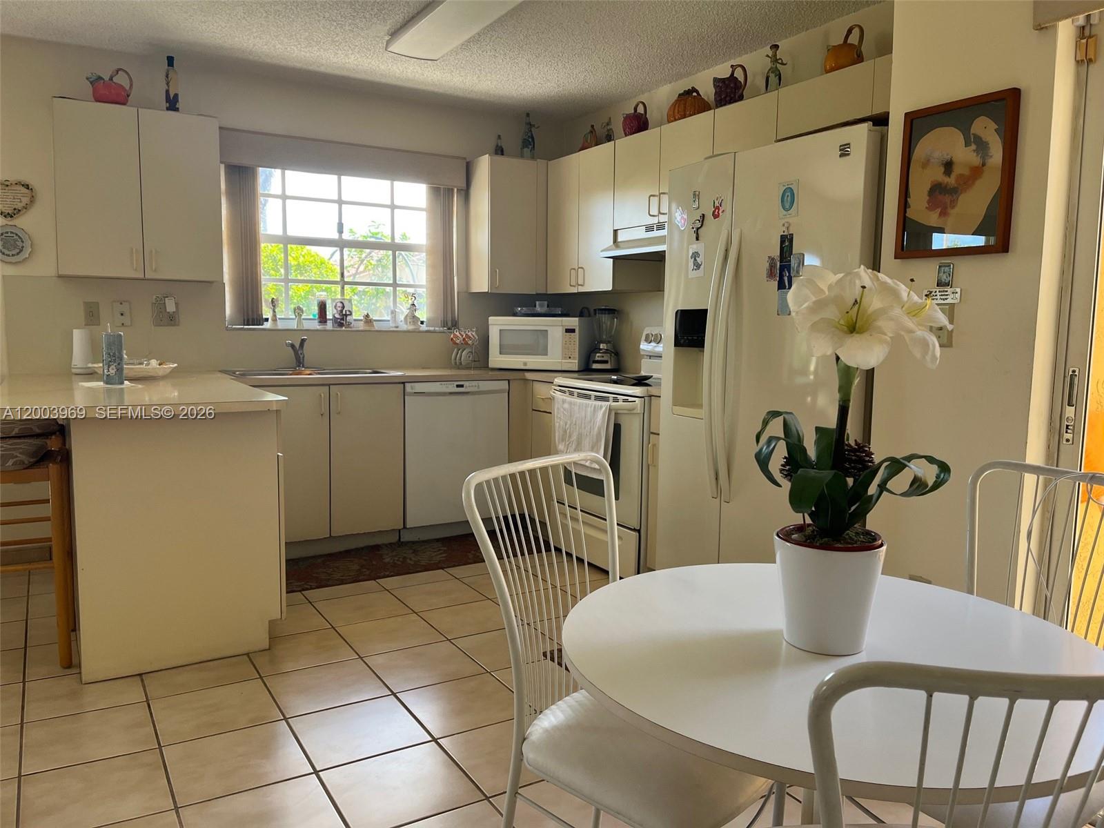 6061 Southwest 128th Court Miami, FL 33183 - Photo 6 of 16 a kitchen with stainless steel appliances granite countertop a dining table chairs and a refrigerator