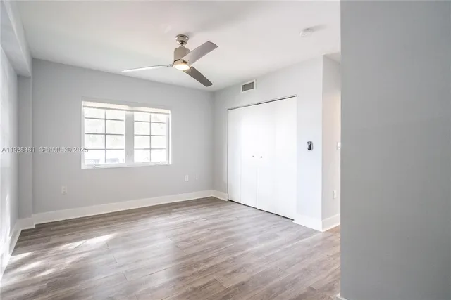 a view of an empty room with wooden floor and a window