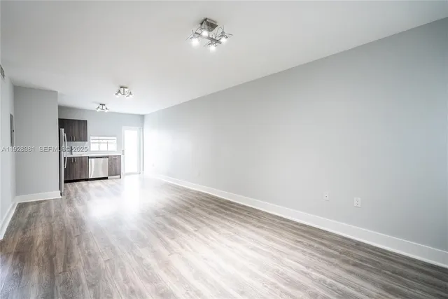 a view of empty room with wooden floor and window