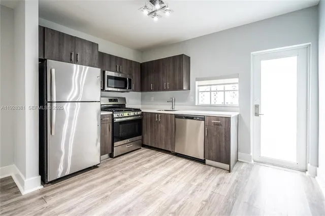 a kitchen with granite countertop a refrigerator oven a sink dishwasher and a stove with wooden floor