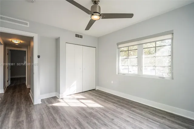 a view of empty room with wooden floor and fan