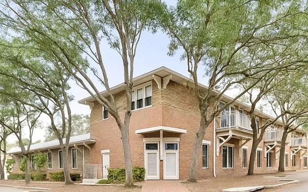 a view of a white house with a large tree