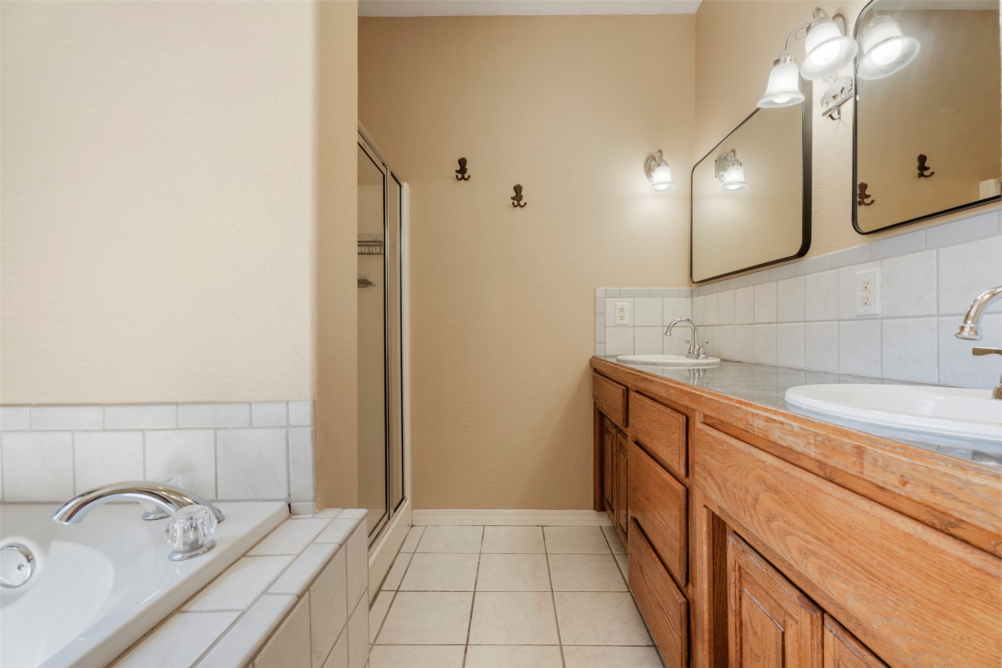 20233 East 570 Road Colcord, OK 74338 - Photo 21 of 39 Dual vanity with individual sinks, wood-finish cabinetry, tile flooring, and a built-in shower enclosure