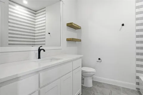 a bathroom with a granite countertop toilet a sink and a mirror