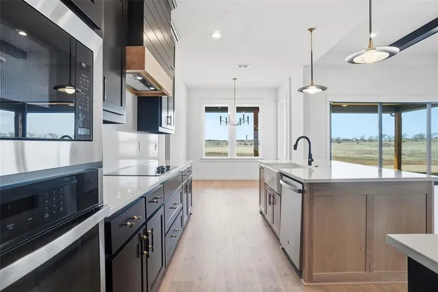 a kitchen with stainless steel appliances granite countertop a sink a stove and a wooden floors