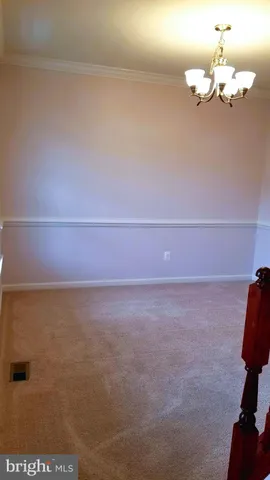 a view of a room with a hanging light and hardwood floor