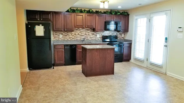 a kitchen with kitchen island granite countertop wooden cabinets and a counter top space