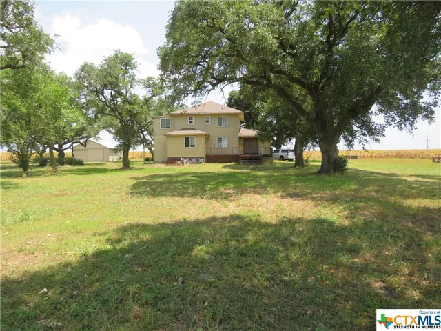 a view of a house with a big yard and large trees