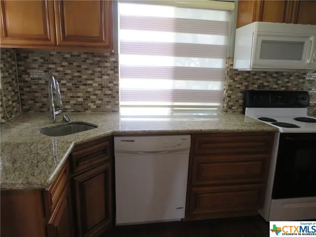 a kitchen with granite countertop a sink and a stove