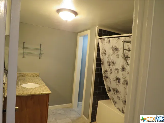 a bathroom with a granite countertop sink and shower curtain