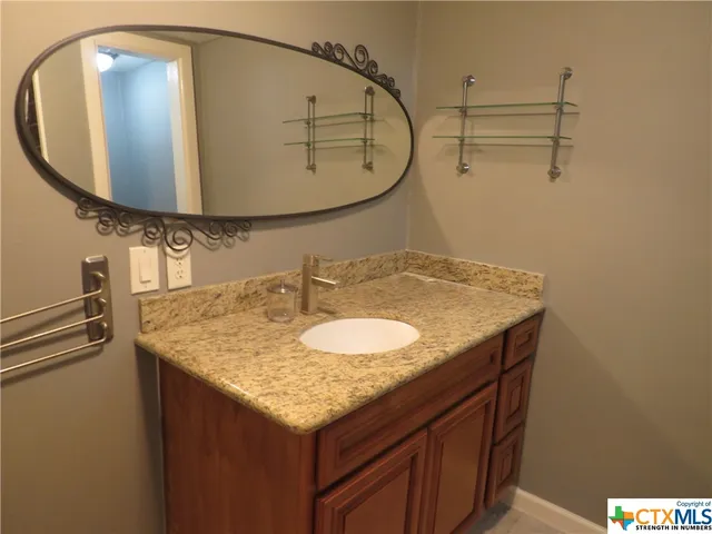 a bathroom with a granite countertop sink and a mirror