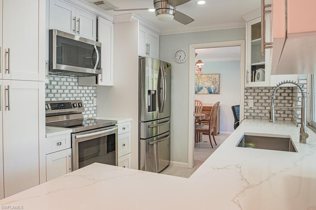 67 Pebble Beach Boulevard Naples, FL 34113 - Photo 11 of 28 Kitchen featuring ceiling fan, a sink, visible vents, appliances with stainless steel finishes, and crown molding