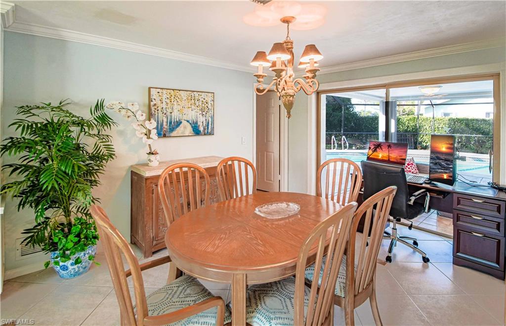 67 Pebble Beach Boulevard Naples, FL 34113 - Photo 13 of 28 Dining space featuring light tile patterned floors, baseboards, ornamental molding, and an inviting chandelier