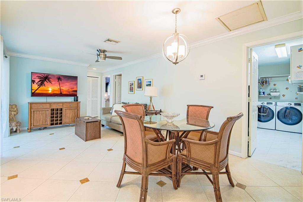 67 Pebble Beach Boulevard Naples, FL 34113 - Photo 15 of 28 Dining space featuring attic access, light tile patterned flooring, ornamental molding, and independent washer and dryer
