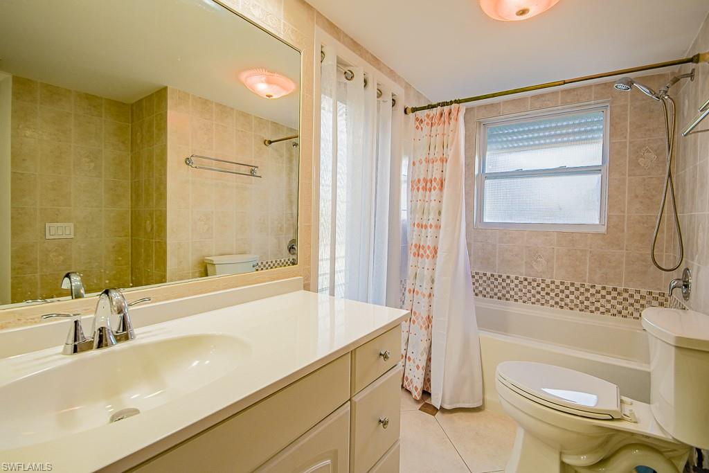 67 Pebble Beach Boulevard Naples, FL 34113 - Photo 19 of 28 Full bath with tile patterned flooring, toilet, vanity, tile walls, and shower / bath combination with curtain