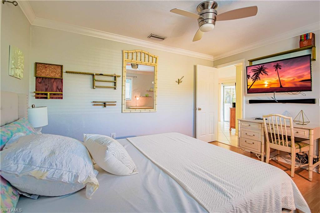 67 Pebble Beach Boulevard Naples, FL 34113 - Photo 22 of 28 Bedroom with a ceiling fan, visible vents, crown molding, and wood finished floors