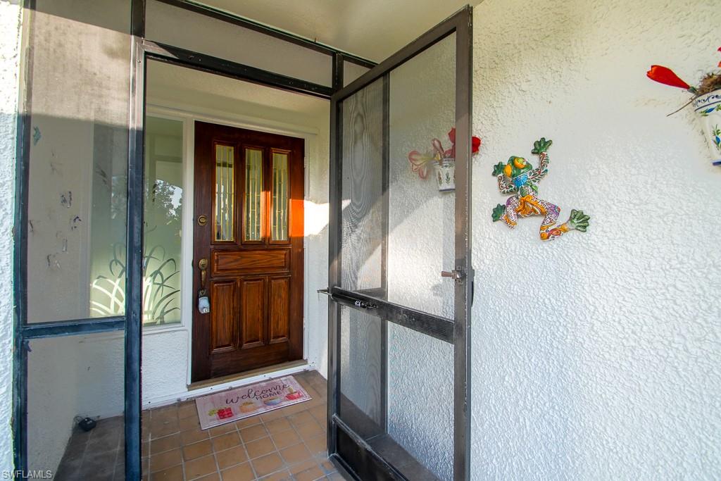 67 Pebble Beach Boulevard Naples, FL 34113 - Photo 3 of 28 View of exterior entry featuring stucco siding