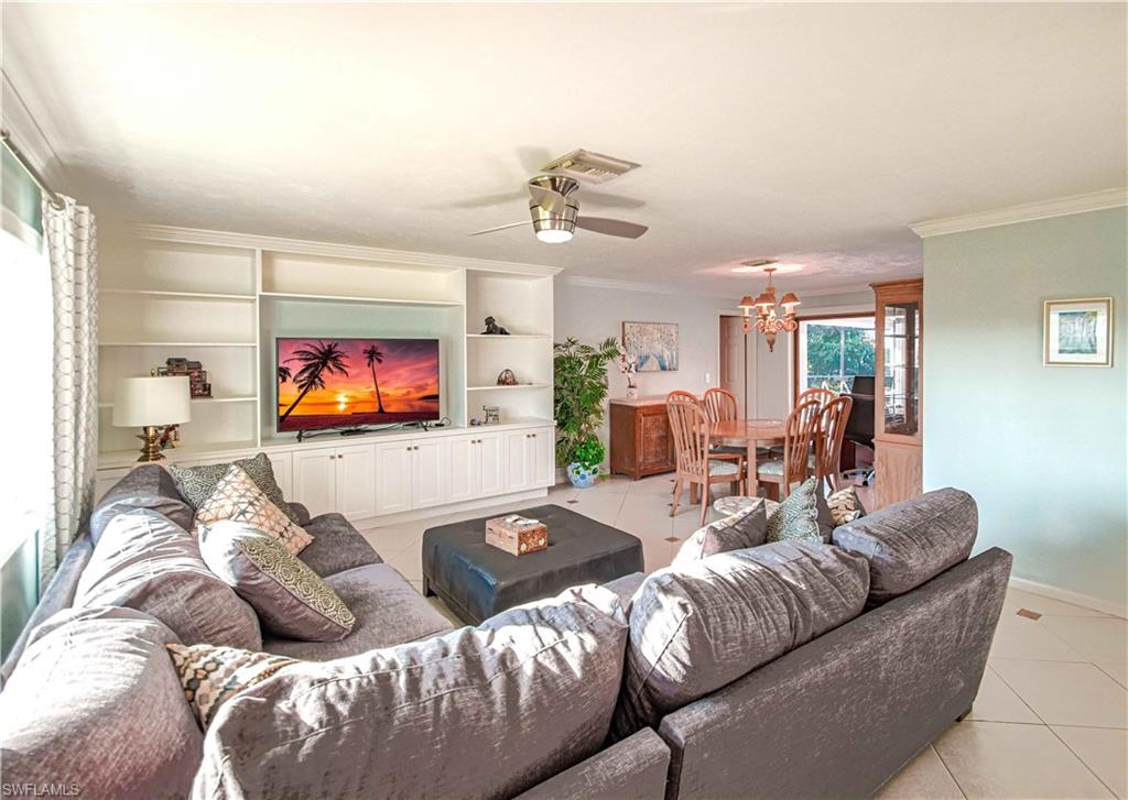 67 Pebble Beach Boulevard Naples, FL 34113 - Photo 4 of 28 Living area with ornamental molding, ceiling fan with notable chandelier, baseboards, and light tile patterned floors