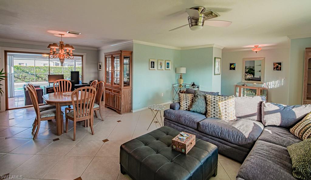 67 Pebble Beach Boulevard Naples, FL 34113 - Photo 7 of 28 Living area featuring ceiling fan with notable chandelier, crown molding, baseboards, and light tile patterned floors