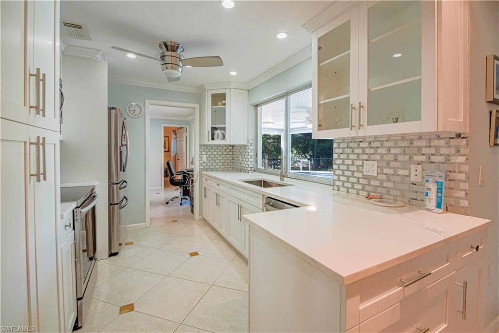 67 Pebble Beach Boulevard Naples, FL 34113 - Photo 9 of 28 Kitchen with light tile patterned floors, stainless steel appliances, a ceiling fan, visible vents, and crown molding