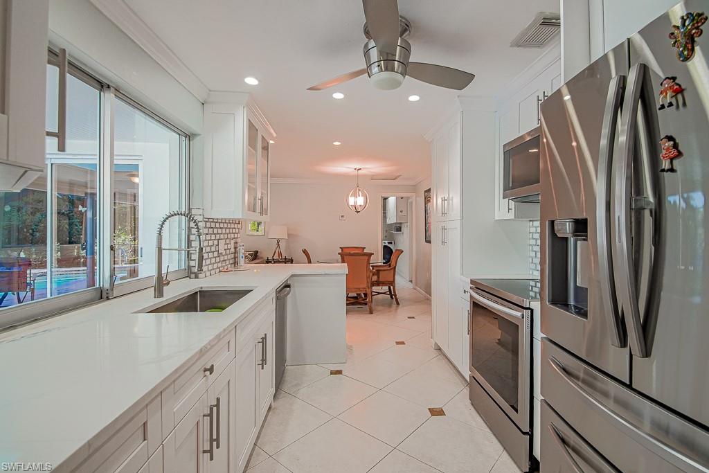 67 Pebble Beach Boulevard Naples, FL 34113 - Photo 10 of 28 Kitchen featuring a sink, visible vents, white cabinets, ornamental molding, and appliances with stainless steel finishes