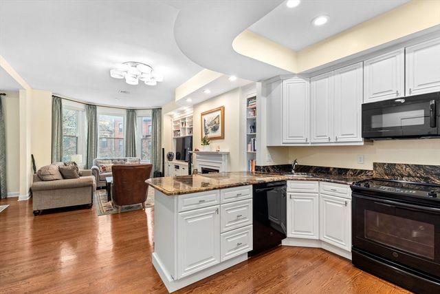 a kitchen with stainless steel appliances granite countertop a stove top oven a sink dishwasher a dining table and chairs with wooden floor