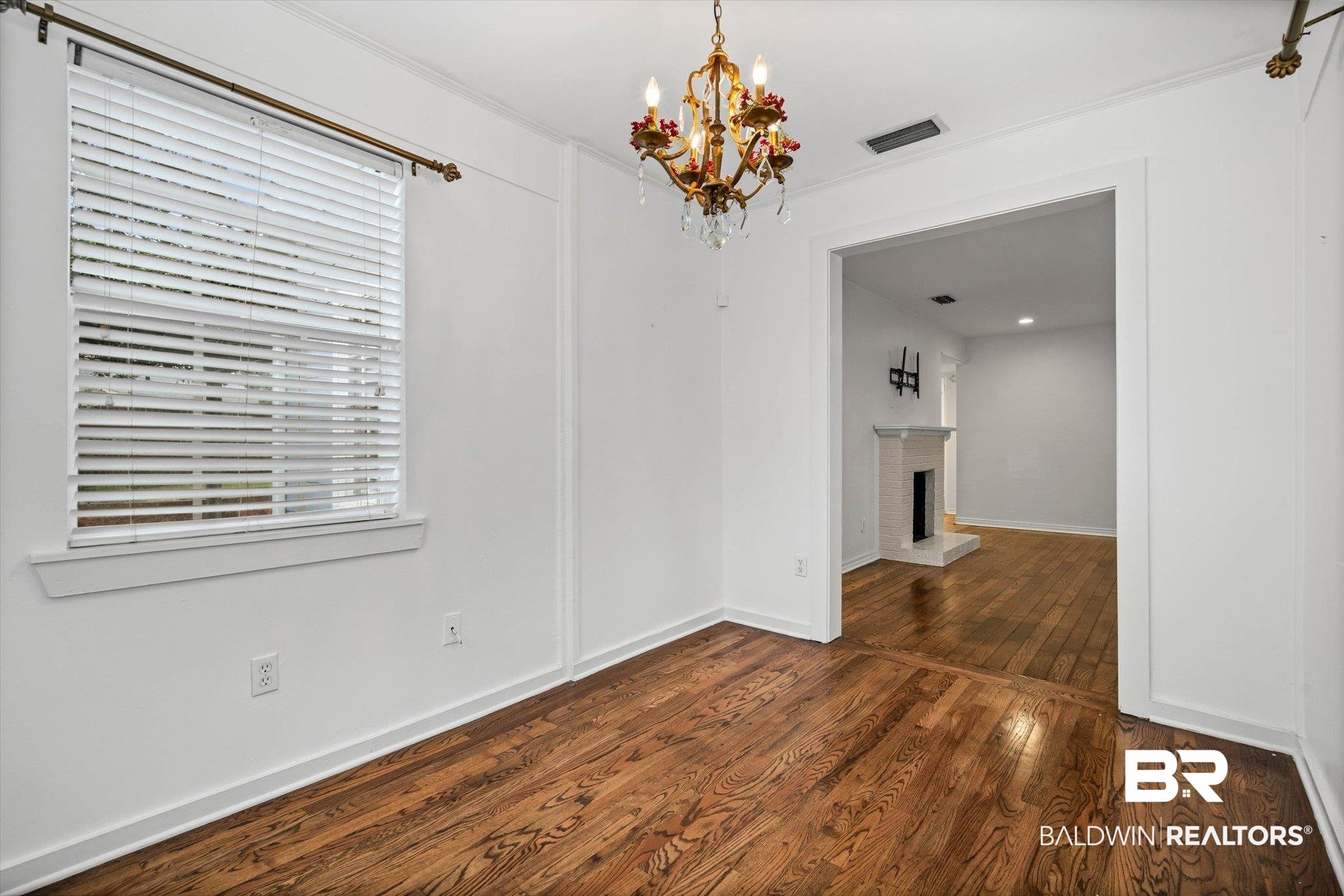 11 York Place Mobile, AL 36608 - Photo 6 of 24 Unfurnished dining area with dark wood-type flooring, a chandelier, and a brick fireplace