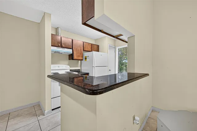 a kitchen with granite countertop a sink stove and refrigerator