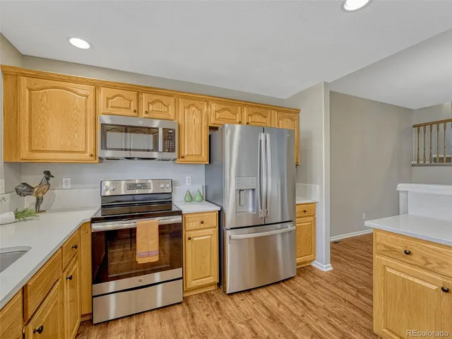 a kitchen with a refrigerator stove and wooden cabinets
