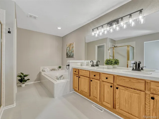 a spacious bathroom with a double vanity sink a mirror a bathtub and shower
