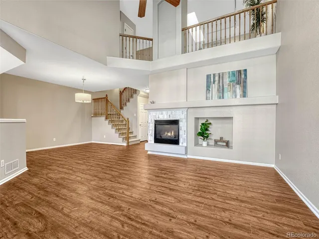 a view of an empty room with wooden floor and a fireplace