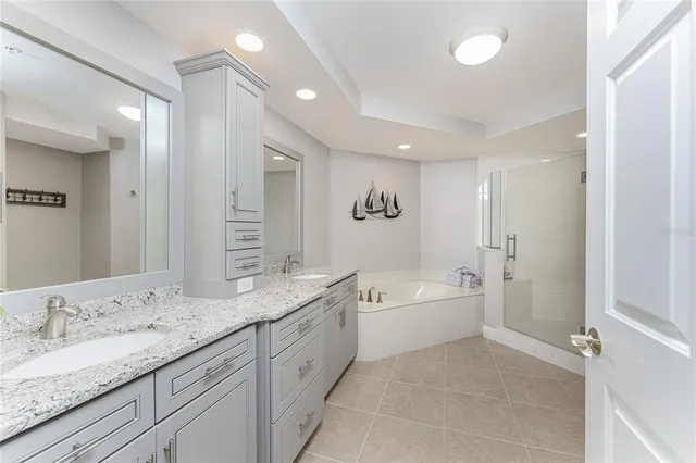 a spacious bathroom with a granite countertop double vanity sink a mirror and a bathtub