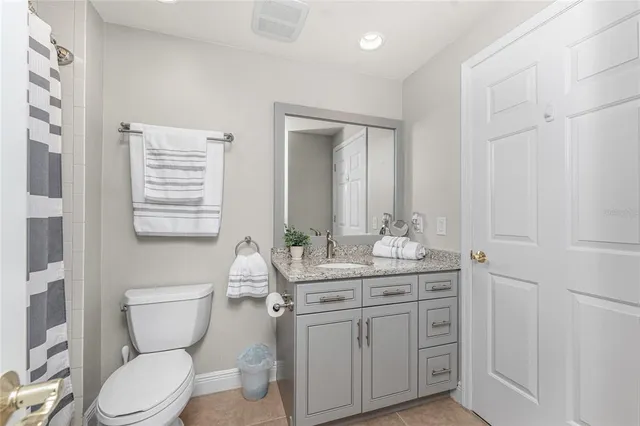 a bathroom with a granite countertop toilet sink and mirror