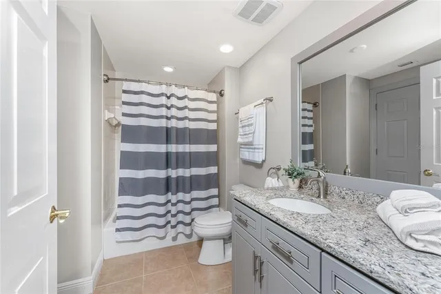 a bathroom with a granite countertop sink a toilet a mirror and shower