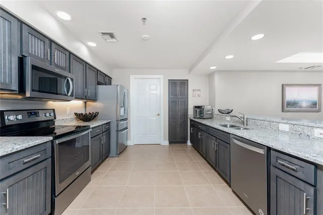 a large kitchen with stainless steel appliances granite countertop a sink stove and refrigerator