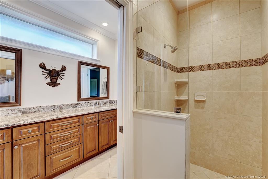 825 Southeast Riverside Drive Stuart, FL 34994 - Photo 28 of 96 a bathroom with a granite countertop sink a mirror and a shower