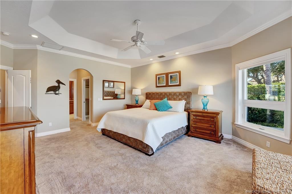 825 Southeast Riverside Drive Stuart, FL 34994 - Photo 35 of 96 a bedroom with a large bed and a chandelier