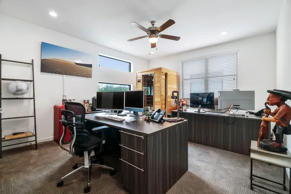 a view of a workspace with furniture and a ceiling fan