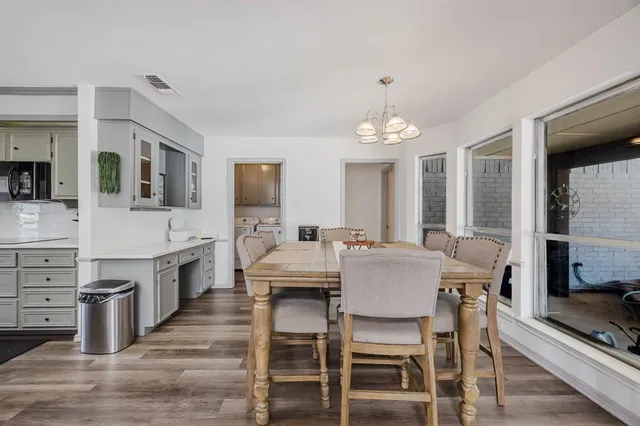 a dining room with wooden floor a chandelier a wooden table and chairs