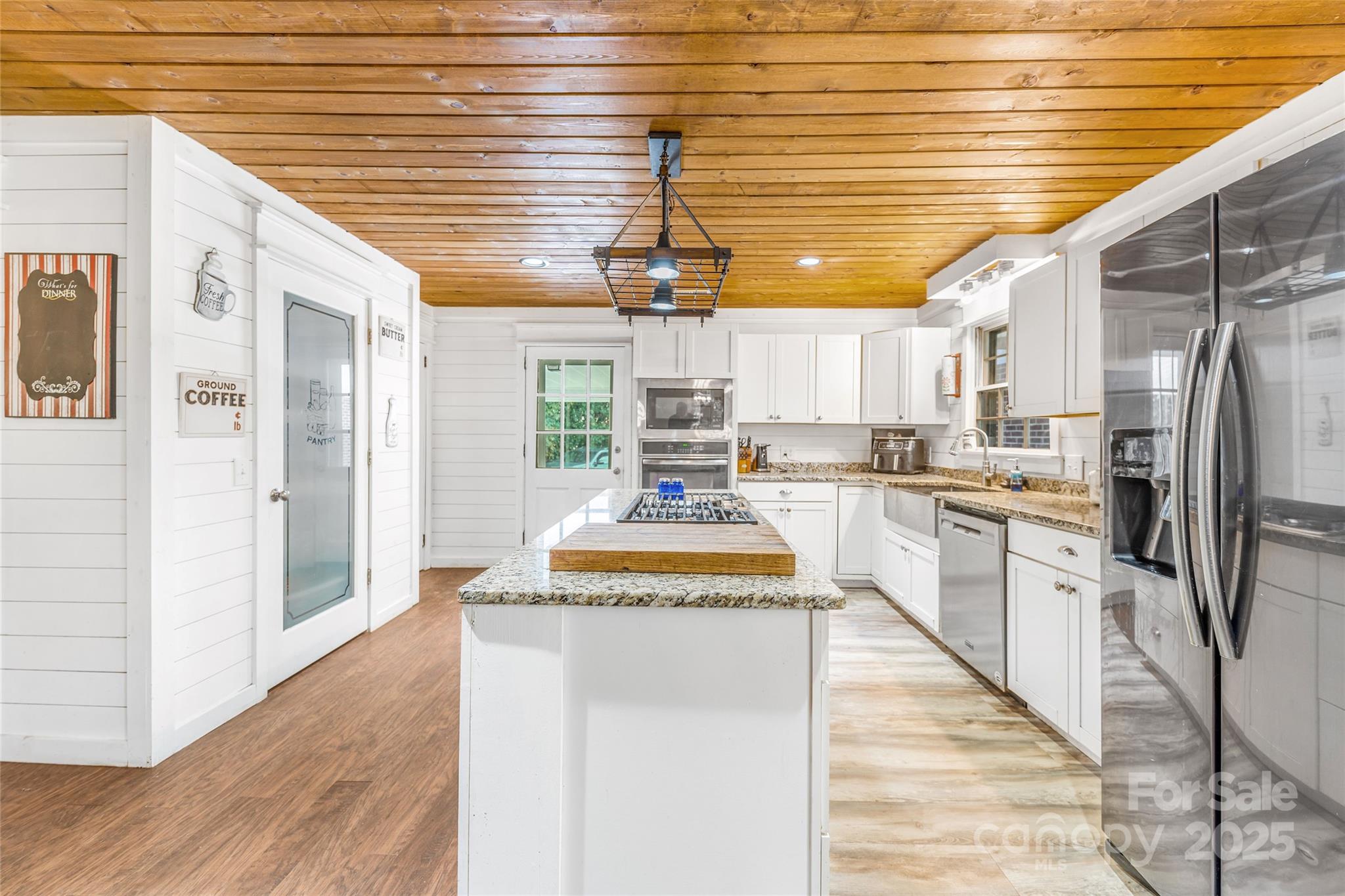 679 Solomon Jones Road Cedar Mountain, NC 28718 - Photo 10 of 47 a kitchen with stainless steel appliances granite countertop a refrigerator a sink dishwasher a stove and white cabinets with wooden floor