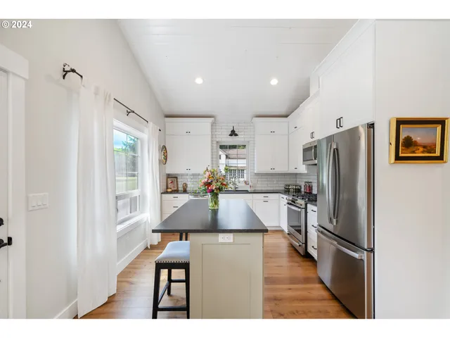 a kitchen with stainless steel appliances granite countertop a refrigerator a stove and a sink