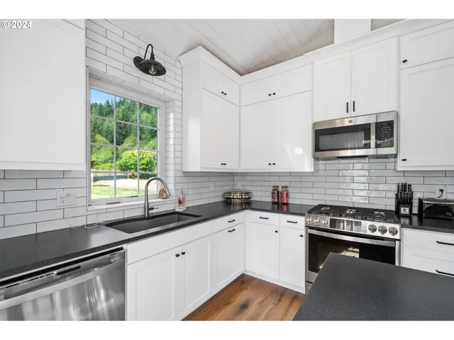 a kitchen with granite countertop a sink a window stainless steel appliances and cabinets