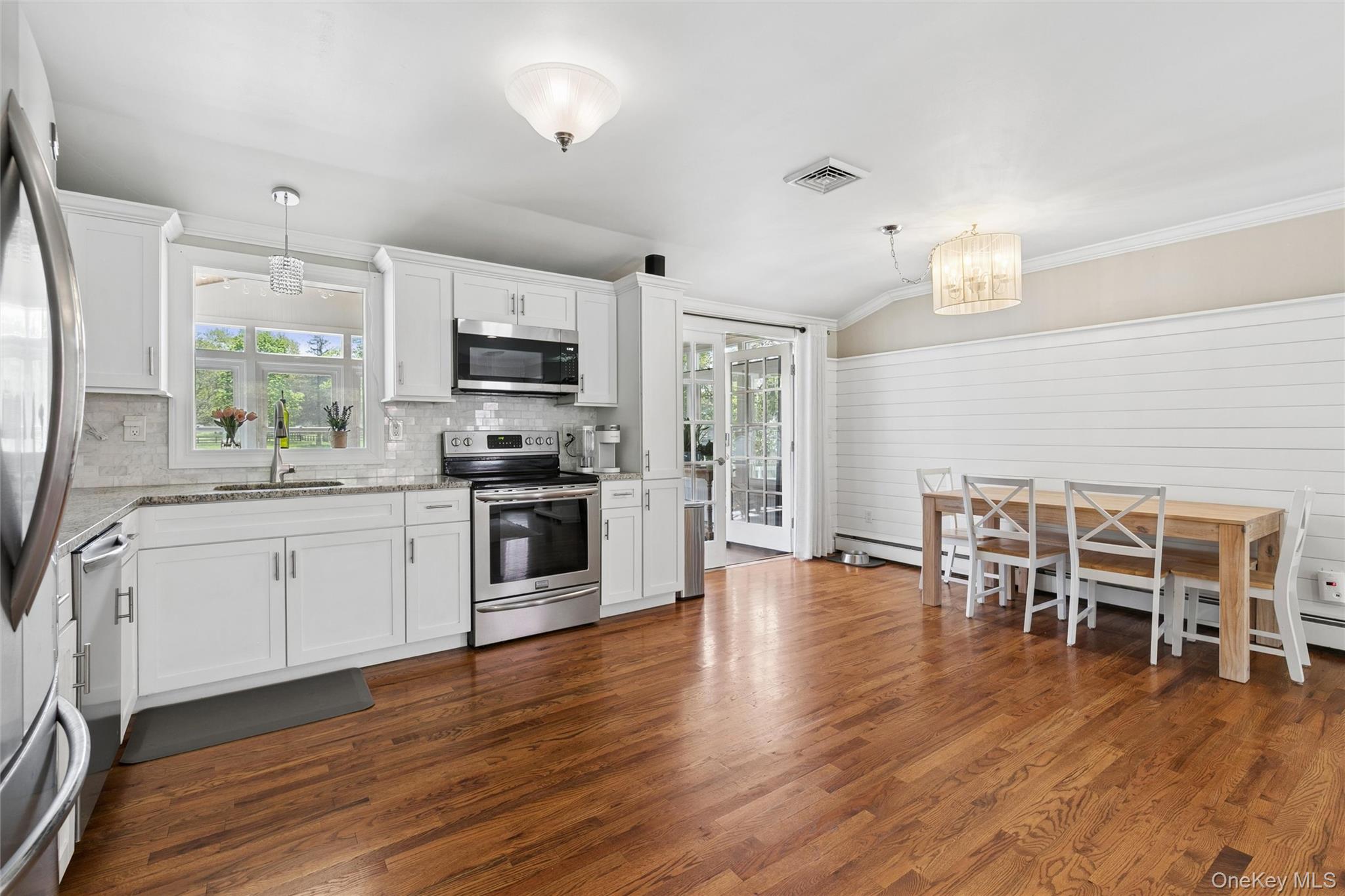 1039 Middle Road Riverhead, NY 11901 - Photo 18 of 34 a kitchen with stainless steel appliances granite countertop a stove top oven a sink a dining table and chairs with wooden floor